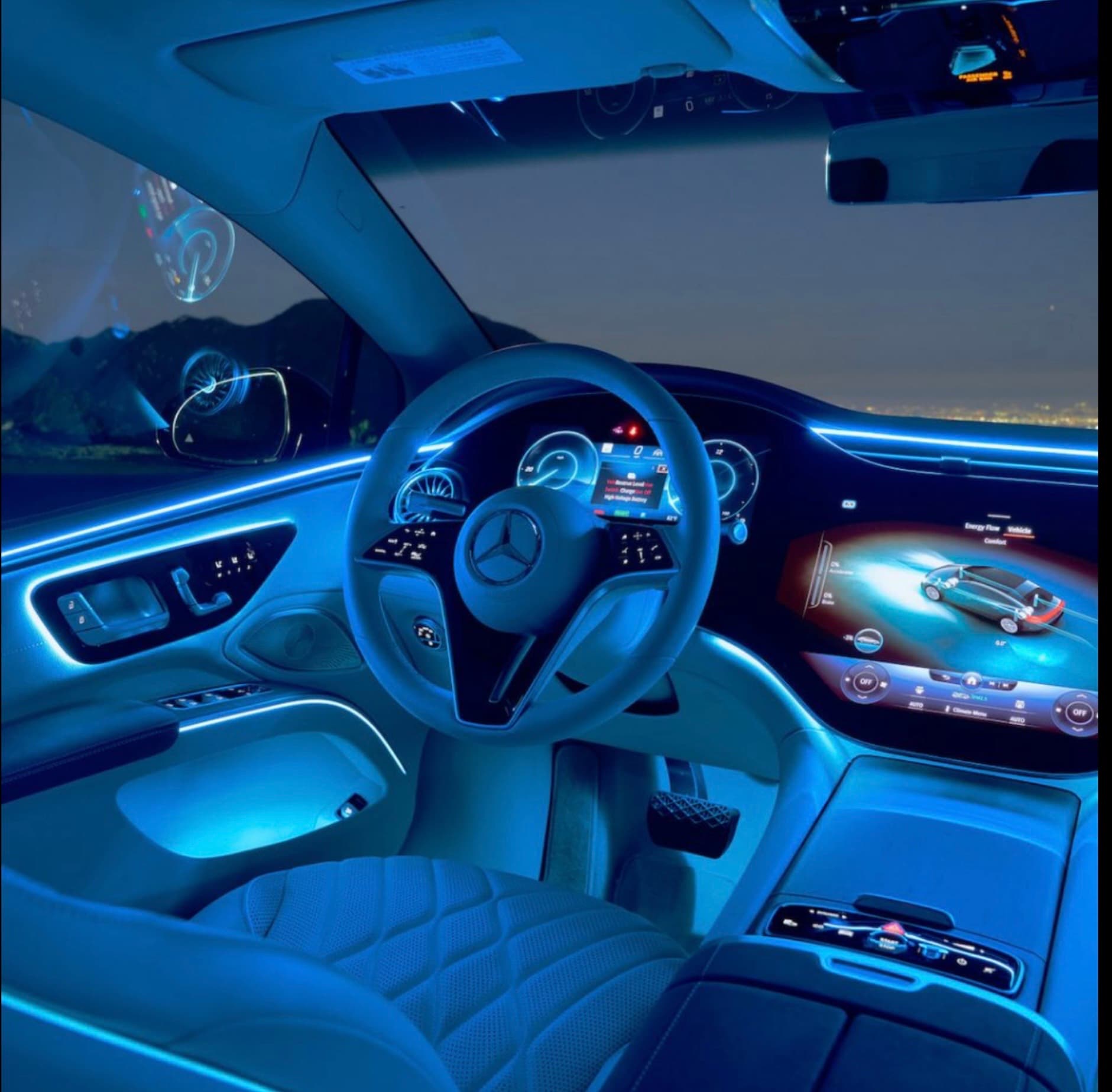 Futuristic Mercedes-Benz interior with blue ambient lighting, digital dashboard screens, and quilted leather seats.