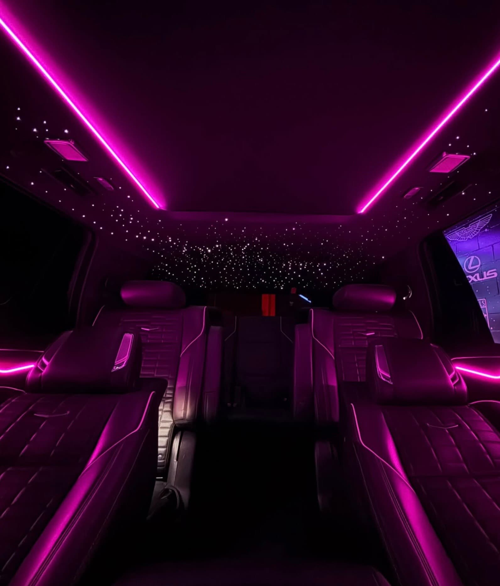 Luxury car interior with purple ambient lighting, leather seats, and a starlight ceiling headliner.